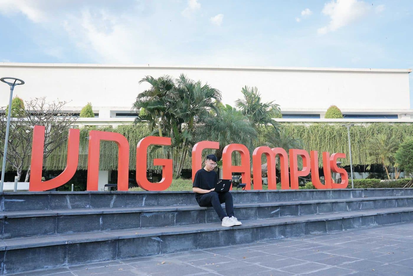 A young builder sitting by the VNG Campus sign